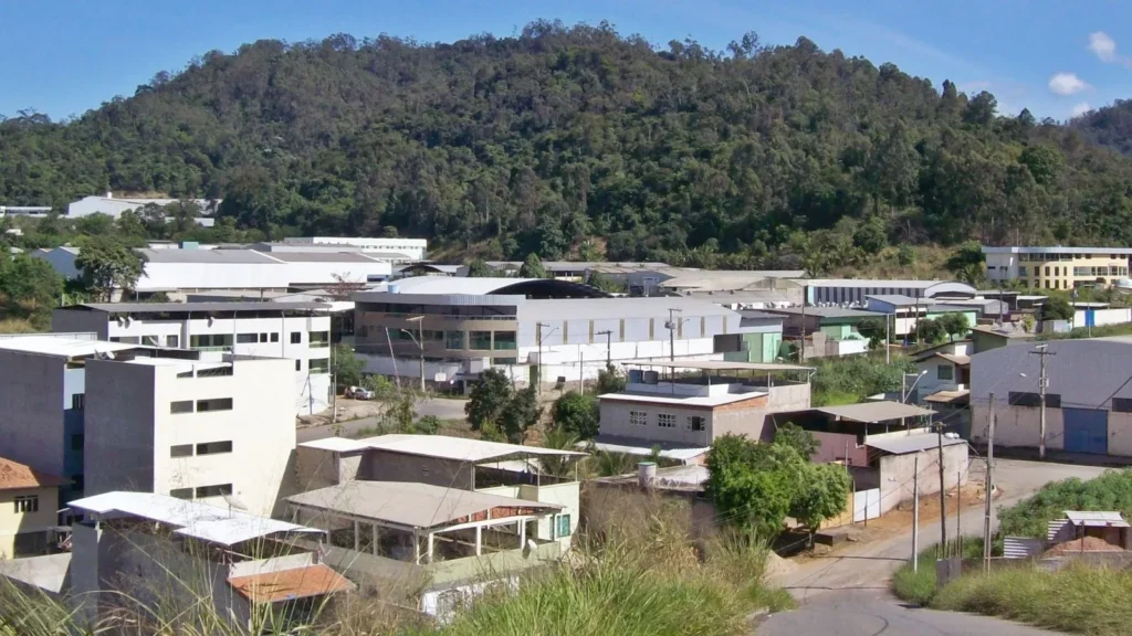 Distrito industrial com galpões e fábricas ao pé de uma serra